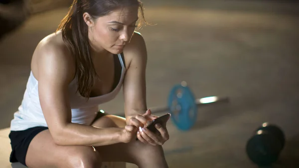 Bela atlético morena usa smartphone enquanto descansando no — Fotografia de Stock