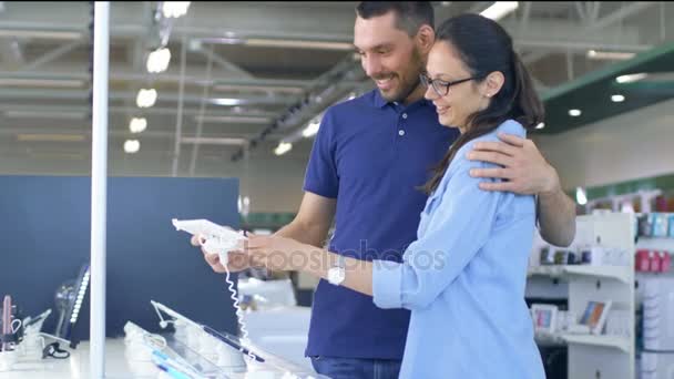 Im Elektronikgeschäft schaut das schöne junge Paar auf neueste Tablet-Computer, sie überlegen, sich einen zu kaufen. Laden ist groß, hell und hat alle neuen Geräte. — Stockvideo