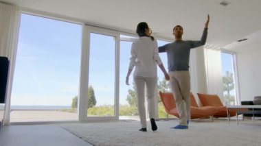 Yeni satın alınan evlerinde güzel genç çift, tavan pencere zemin ile denizde görünüyorlar. Parlak, Modern iç zevkle yapılmış onların lüks ev mı.