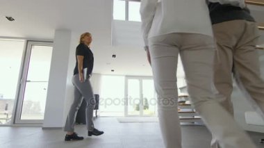 Profesyonel emlakçı gösterir şık Modern ev satın alma / yeni ev kiralamak için piyasada olan güzel genç bir çift için. Evin kat tavana uzanan pencereler ve sahil görünümü vardır.