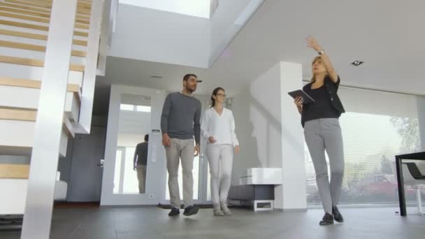 Agente inmobiliario muestra elegante casa moderna a una hermosa pareja joven que están interesados en la compra / compra / alquiler . — Vídeo de stock