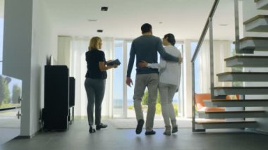 Profesyonel emlakçı gösterir şık Modern ev satın alma / yeni ev kiralamak için piyasada olan güzel genç bir çift için. Evin kat tavana uzanan pencereler ve sahil görünümü vardır.