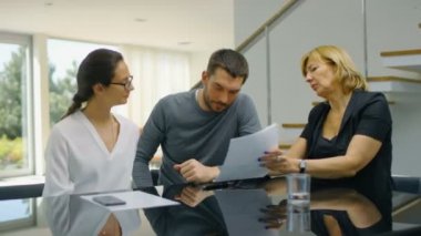 Oturma odası emlakçı ve güzel genç çift oturum tablosunda, belgelerin oturmak. Sunny ve parlak evim.