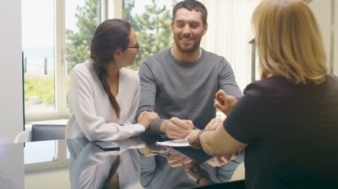 Masada oturan yaşam işaretleri sözleşme güzel genç çift ve satın House, emlakçı evin anahtarları verir. Yeni evli mutlu kucaklamak. Sunny ve parlak evim. 
