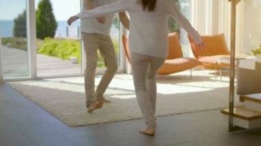 Güneşli oturma odasında, yakışıklı genç Spin-sarılmak onun güzel kız arkadaşı ve onlar kaldırdı. Onlar mutlu ve Sunny Deniz Manzaralı evim.