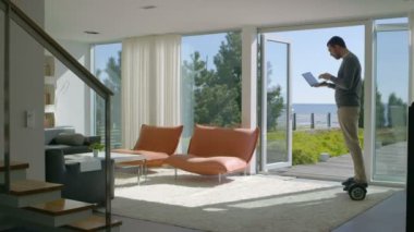 Teknoloji sanayi işadamı çalışma ev kullanır dizüstü bilgisayar ve evin etrafındaki Rides onun Gyro Scooter üzerinde. Modern evini sahil görünümü vardır.
