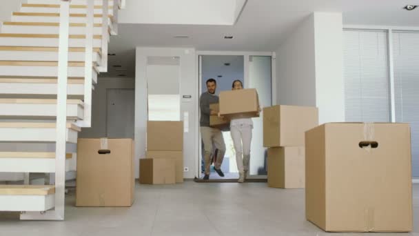 Lyckligt par flytta lådor med saker i sina nya ljusa och moderna hus. En massa rutor redan stå i rummet. — Stockvideo