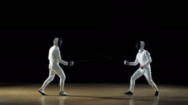 İki profesyonel eskrimcilerin ustalıkla folyo ile mücadele. Siyah arka plan üzerine izole atış. 