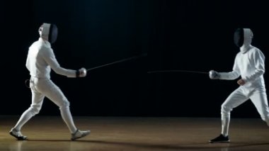 İki profesyonel eskrimcilerin göstermek ustaca kılıç onların folyo Fight. Bir güzel Fleche saldırı yapar. Siyah arka plan üzerine izole atış.