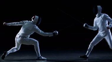 İki profesyonel tam donanımlı eskrimcilerin ustalıkla folyo ile mücadele. Atış yavaş hareket ve siyah arka plan izole. 