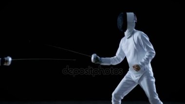 İki profesyonel eskrimcilerin göstermek ustaca kılıç onların folyo Fight. Onlar sıçrama ve itme ve saldır. Siyah arka plan üzerine izole atış .