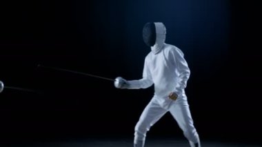 İki profesyonel eskrimcilerin göstermek ustaca kılıç onların folyo Fight. Onlar sıçrama ve itme ve saldır. Siyah arka plan üzerine izole atış .