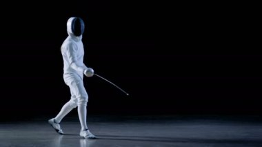 Yetenekli Fencer eğitim bir folyo ile tam donanımlıdır. O uygulamaları saldırı, savunma, sıçrama, itme ve saldır. Siyah arka plan üzerine izole atış.