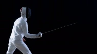 Tam donanımlı bir yetenekli Fencer eğitim onun saldırı ve hamle yan görünüm bir folyo ile. Siyah arka plan üzerine izole atış.
