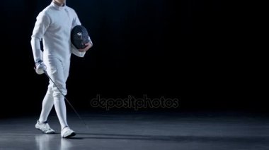 Bir genç eskrimci maskesini tutarak ve seyirci folyo kılıcıyla tebrik portre vurdu. Siyah arka plan üzerine izole atış.