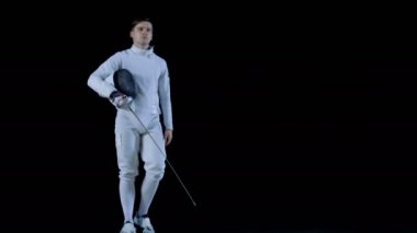 Portre çekim bir genç eskrimci yürüyüş içine odak süre tutarak onun koruyucu maske onun kol ve sonra koyarak onu Tarih ve hamle saldırı yapma. Siyah arka plan üzerine izole atış.