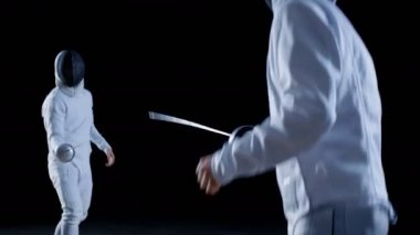 İki profesyonel tam donanımlı eskrimcilerin ustalıkla folyo ile mücadele. Onlar saldırı, savunma, sıçrama, itme ve saldır. Siyah arka plan üzerine izole atış. 