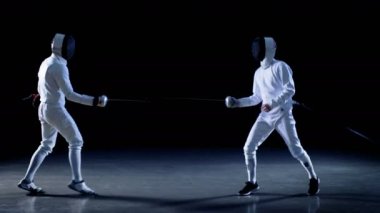 Şampiyonluk iki profesyonel tam donanımlı eskrimcilerin ustalıkla mücadele ile üzerinde sayısı puanları çetele tutar Foils. Onlar saldırı, savunma, sıçrama, itme ve saldır. İzole siyah arka plan üzerine ateş. 