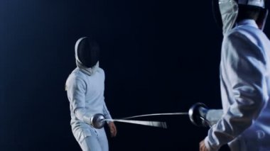 İki profesyonel tam donanımlı eskrimcilerin ustalıkla folyo ile mücadele. Onlar saldırı, savunma, sıçrama, itme ve saldır. Siyah arka plan üzerine izole atış. 