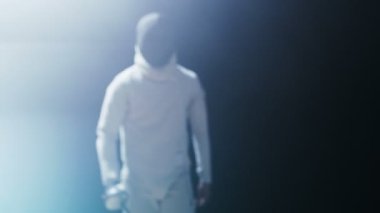 Bir tam donanımlı yetenekli Fencer eğitim karanlık Himl etrafında ise bir spot ışığı bir folyo ile portre vurdu. O uygulamaları saldırı, savunma, sıçrama, itme ve saldır. Siyah arka plan üzerine izole atış.