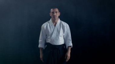 Portre çekim, Aikido geleneksel samuray Hakama giyen ana kamera ve saygı yay yürüyüşler giysiler. Onu o spot karanlık çevreler. Siyah arka plan üzerine izole atış.