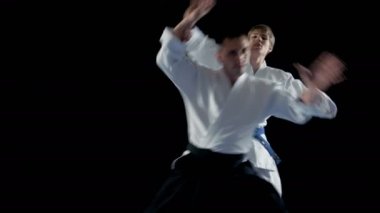 Dövüş sanatları ustası geleneksel samuray Hakamas giyen genç öğrenci Aikido teknik Defening kendini saldırmak arkadan öğretir. Siyah arka plan üzerine ve yavaş hareket izole atış. 