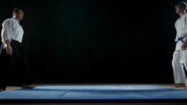 Dövüş sanatları ustası geleneksel samuray Hakamas ve onun genç öğrenci yay birbirlerine ve almak savaş duruş giyiyor. Siyah arka plan üzerine ve yavaş hareket izole atış. 