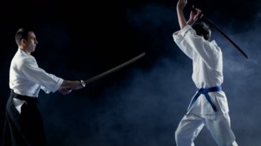 Dövüş sanatları ustası genç öğrencisini öğretir nasıl tahta kılıcı dışkı ile mücadele yapılır. Fikir tartışması saniyede, Master WINS biter. Siyah arka plan üzerinde atış izole.