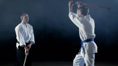 Dövüş sanatları ustası genç öğrencisini öğretir nasıl tahta kılıcı dışkı ile mücadele yapılır. Fikir tartışması saniyede, Master WINS biter. Atış siyah arka plan üzerinde izole ve yavaş hareket.