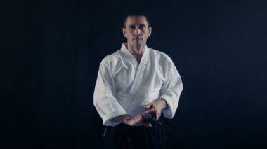 Portre çekim Aikido Ana giyen geleneksel samuray Hakama giysiler alır onun Japon kılıç kılıç kını ve hali ile o. Onu o spot karanlık çevreler. Siyah arka plan üzerine izole atış.