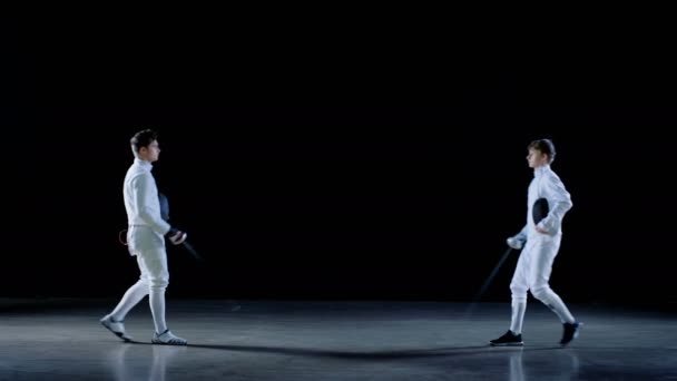 Two Young Professional Fencers Greet Audience, Put on Masks and Start Sword Fighting Match. Shot Isolated on Black Background . — Stock Video