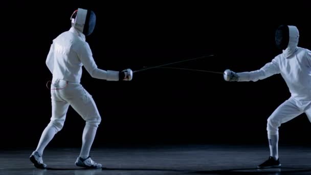 两个专业击剑运动员展示高超剑术在他们铝箔战斗。孤立在黑色背景上和在慢动作镜头. — 图库视频影像