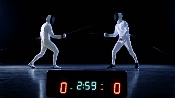 On the Championship Two Professional Fully Equipped Fencers Expertly Fight with Foils while Scoreboard Shows Hits. They Attack, Defend, Leap, Thrust and Lunge. Shot Isolated on Black Background. — Stock Video