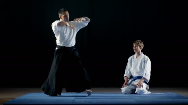 Mistr bojových umění ukazuje krásné Aikido bojové techniky k jeho Student, který se dívá na něj s nejhlubší úctu. Shot izolované na černém pozadí. — Stock video