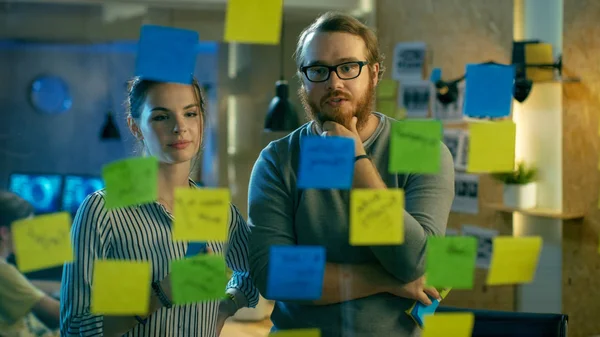 Erkek ve kadın tasarımcılar bir cam Wal üzerinde onların sonraki proje planı