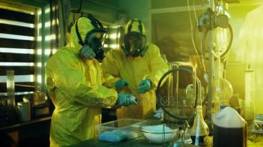 Yeraltı laboratuvarda koruyucu maskeler ve tulum giyen iki gizli kimyagerler paketi çanta sentezlenen Crystal meth kutuları daha fazla dağıtım için. Laboratuvar tam, yasadışı cihazıdır. Onlar terk edilmiş bir binada ağız kavgası.