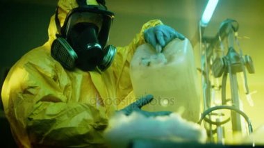 Yeraltı uyuşturucu laboratuarında gizli kimyager koruyucu maske ve Coverall Kimyasalları karıştırır. O teneke kutu sıvı kasenin içine dökülen, duman toksik bileşikler oluşturun. O terk edilmiş binada çalışıyor.