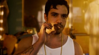 Acımasız çete üyesi Altın zincir ile sigara kameraya meydan okuma ile görünüyor. Yeraltı uyuşturucu laboratuvarı arka planda olduğunu.