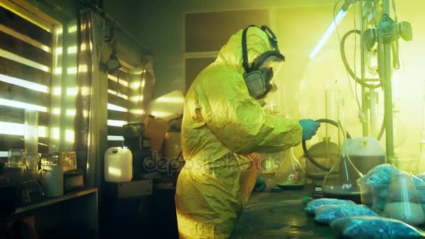 In the Underground Laboratory Two Clandestine Chemists Wearing Protective Coveralls and Masks Cook Drugs. They Work with Beakers, Distillation Glassware, Canisters and Hosepipe. True Crime Concept. — Stock Video