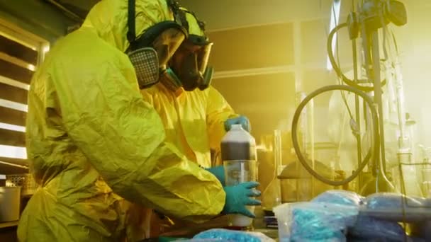W podziemnym laboratorium lek dwa tajne chemików Mix substancji chemicznych podczas gotowania narkotyki. Korzystają, kanistry i zlewki, toksyczne związki tworzenia dymu. Pracują w opuszczonym budynku. — Wideo stockowe
