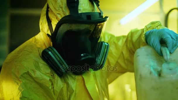 In het laboratorium van de ondergrondse Drug mengt clandestiene chemicus dragen beschermend masker en overall chemicaliën. Hij giet vloeistof uit de bus in kom, toxische verbindingen maken rook. Hij werkt in de verlaten gebouw. — Stockvideo