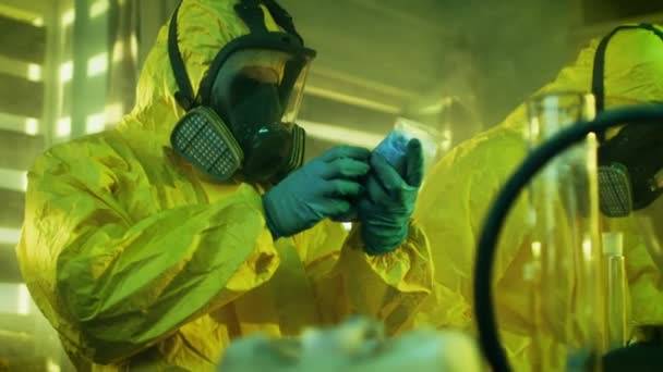 Dans le laboratoire clandestin de drogue Clandestine Chemist portant masque protecteur et combinaison tient sac avec Blue Meth Amphétamine. Son équipe synthétise des substances illégales dans le bâtiment abandonné . — Video