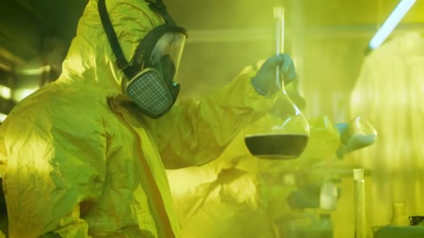 In de ondergrondse Drug laboratorium Team van clandestiene chemici Synthesises illegale Drugs, de één houdt bekerglas met chemicaliën en controles is consistentie. Ze koken Drugs in de verlaten gebouw. — Stockvideo