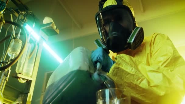 I underjordiska drog laboratoriet blandar hemliga kemist bär skyddande Mask och overall kemikalier. Han häller vätska från kapseln i skål att göra ny sats av syntetisk narkotika. Han hukar i övergivna byggnaden. — Stockvideo
