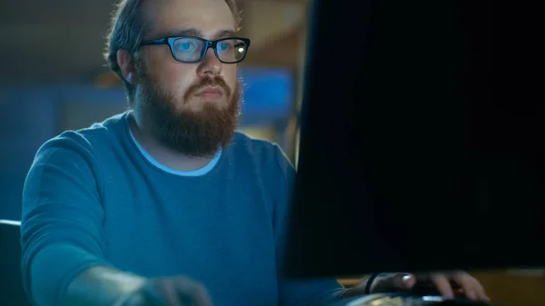 Focused Young Man trabalha em um computador pessoal. Ele usa óculos. — Fotografia de Stock