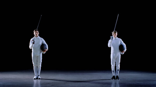 Two Young Professional Fencers Greet Audience, and Preparing for Fighting Match. Shot Isolated on Black Background.