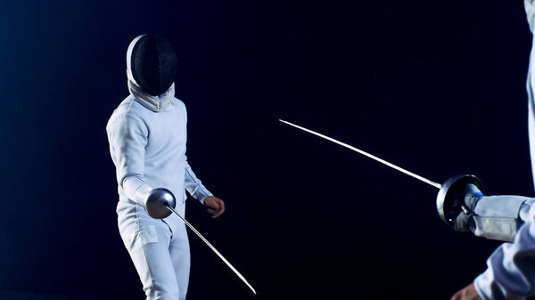 Two Professional Fully Equipped Fencers Fight with Foils. They Attack, Defend, Leap, Thrust and Lunge. Shot Isolated on Black Background.