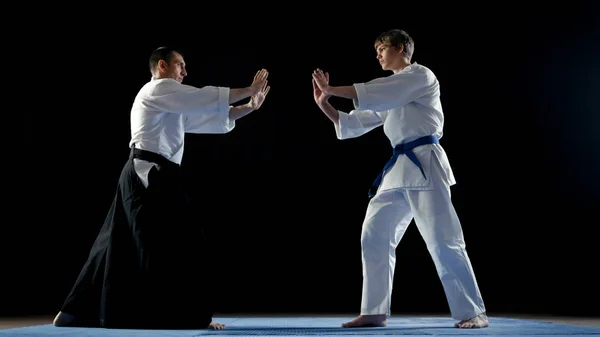 Maestro de artes marciales que usa samuráis tradicionales Hakamas y su joven estudiante adoptan la postura de batalla. Disparo aislado sobre fondo negro . —  Fotos de Stock