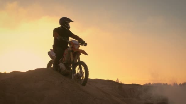 プロフェッショナル モトクロス バイク見事の上に立つ彼のエンデューロ バイクでオフロードの砂丘。遠くに見える、全軌跡します。. — ストック動画