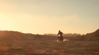 Profesyonel motokros motosiklet binici Off-Road kum arazi üzerinde kullanıyor. Günbatımı ve şarkı duman, sis ve puslu güneş ışığı ile kaplı olmasıdır.